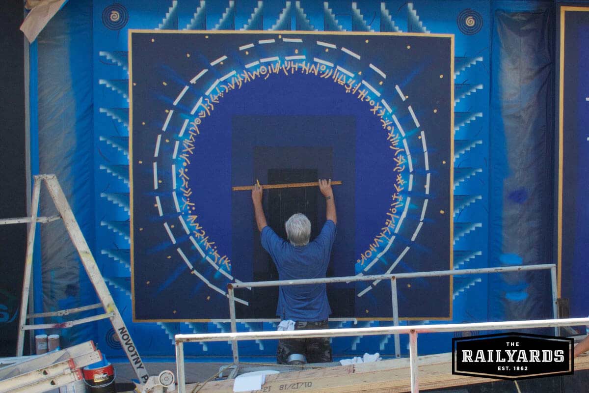 An artist painting a large blue mural. Learn more about Wide Open Walls 2018.