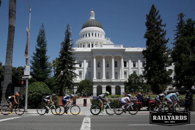 Image features cyclists in front of the California state capital. Learn more about bike month in Sacramento.