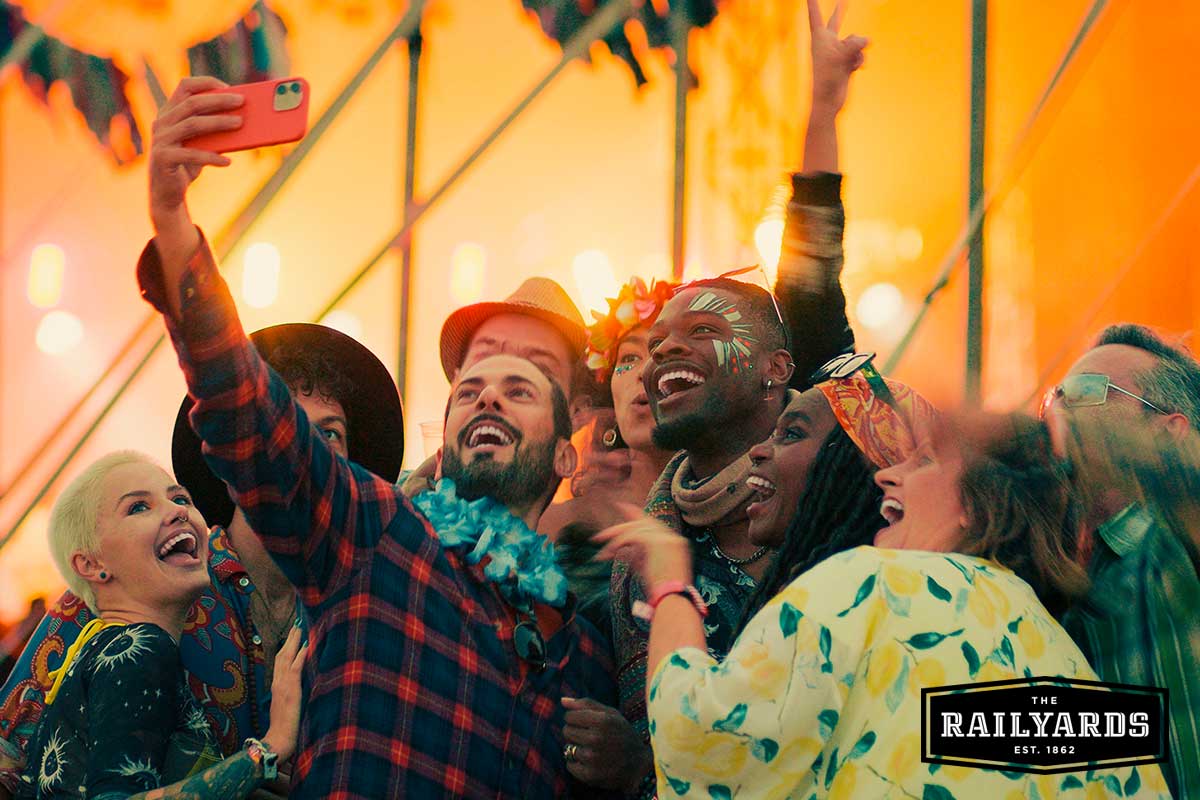 People taking a selfie in the crowd of a music festival.