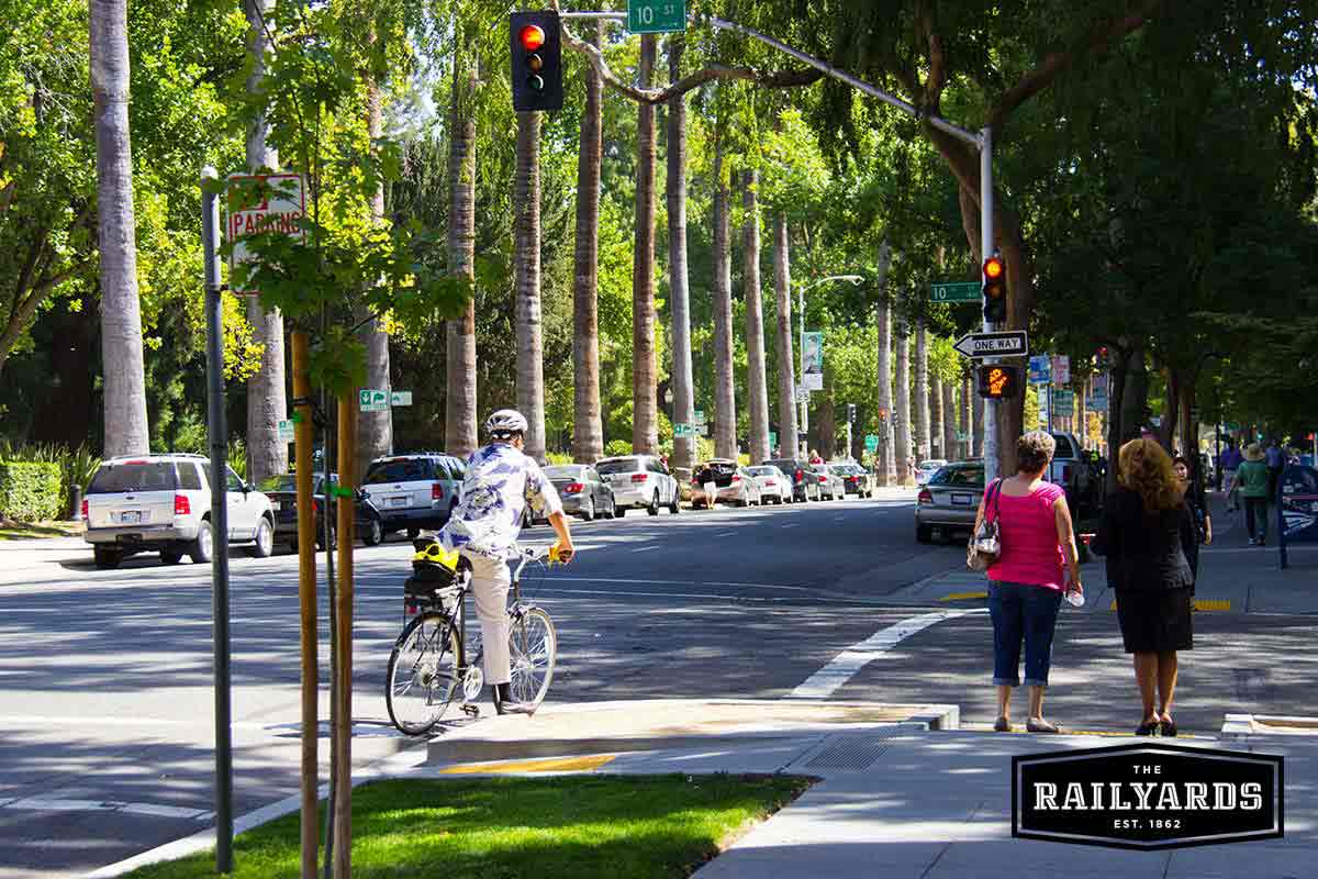 A man rides his bike on a sidewalk in Sacramento. Discover the best bike trails in Sac.