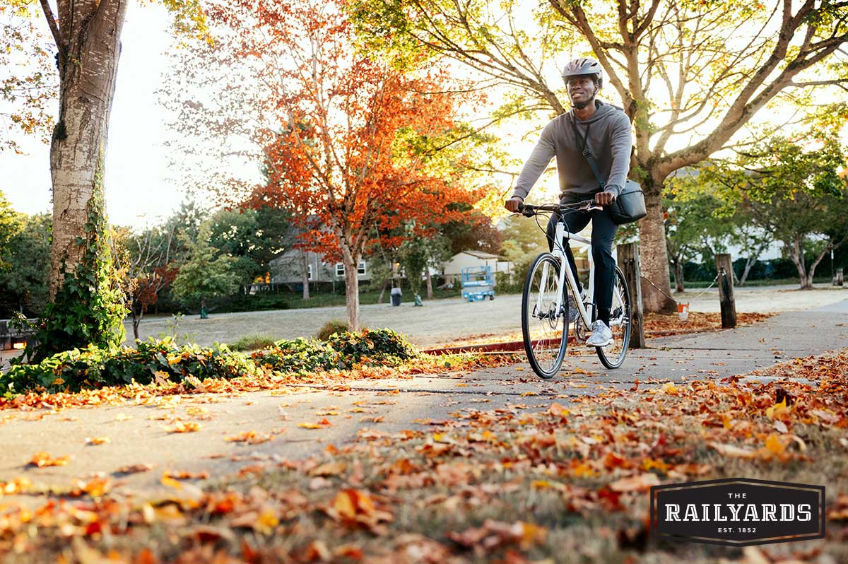 A man riding his bike on the street in autumn.