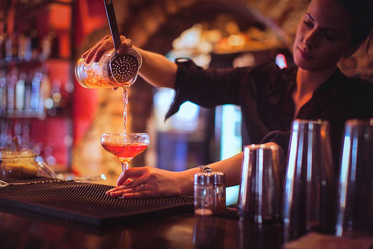 Woman pouring a drink behind the bar.